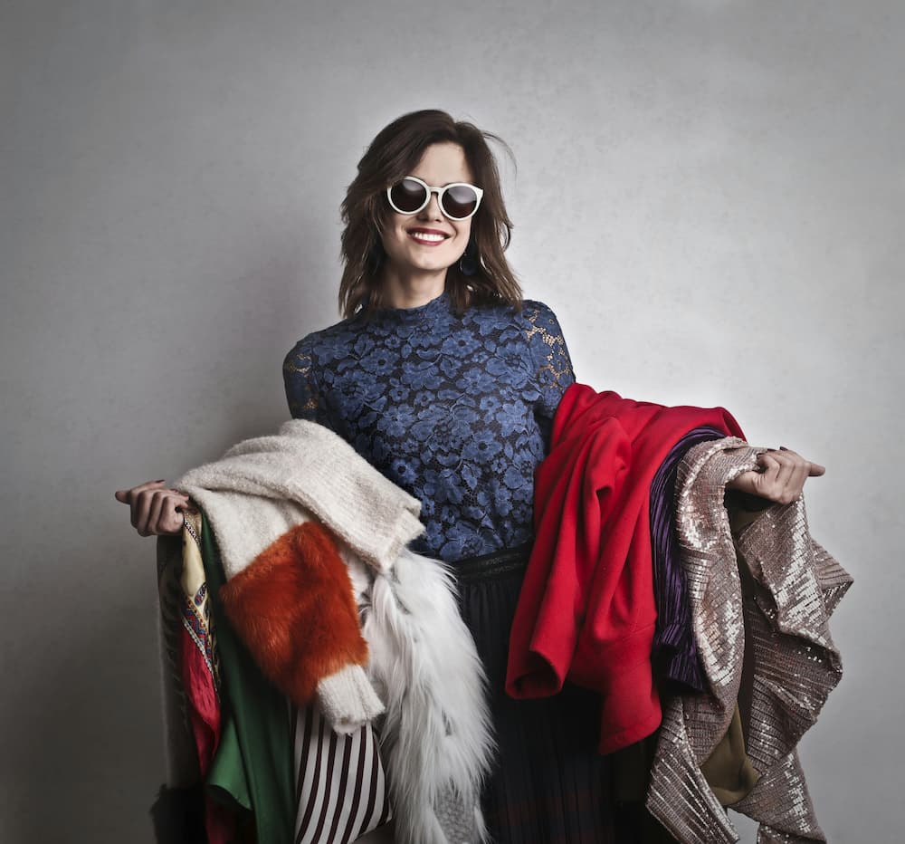 Woman in sunglasses with armful of clothes